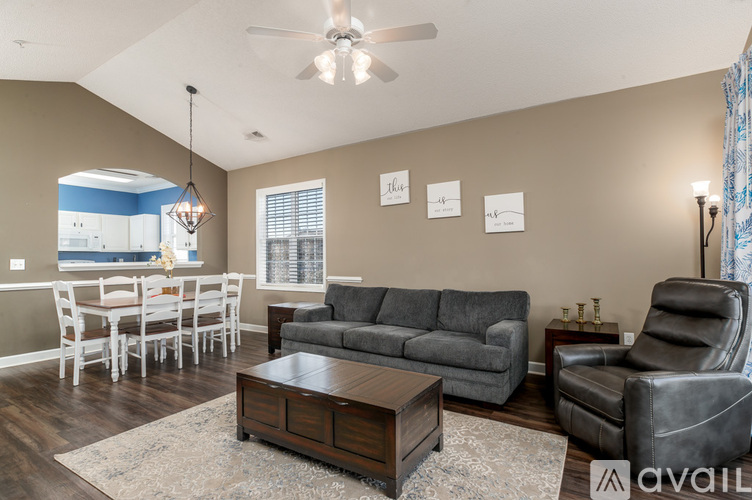 A living room with a grey couch, a coffee table, and a dining table with chairs.