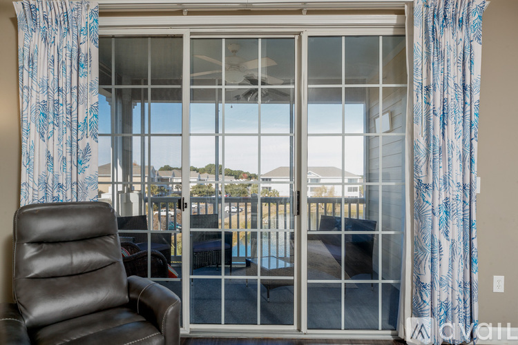 A chair is in front of a window with a view of a pool and buildings.
