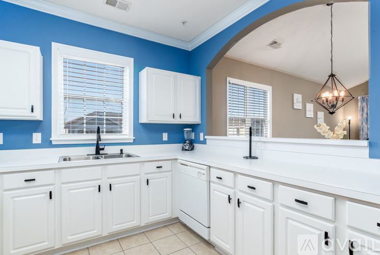 A kitchen with white cabinets and a blue wall.