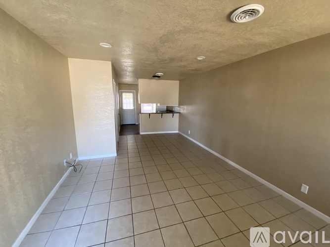 A spacious room with beige walls and a tiled floor.
