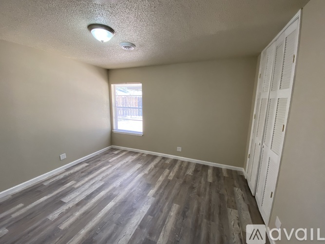 A room with wooden flooring and a window letting in natural light.