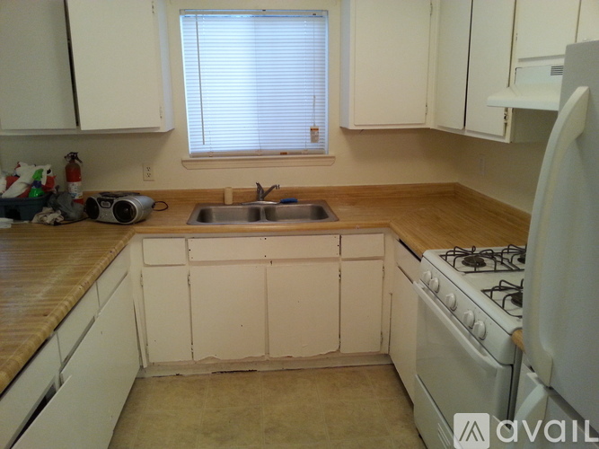 A kitchen with a white stove and white cabinets.