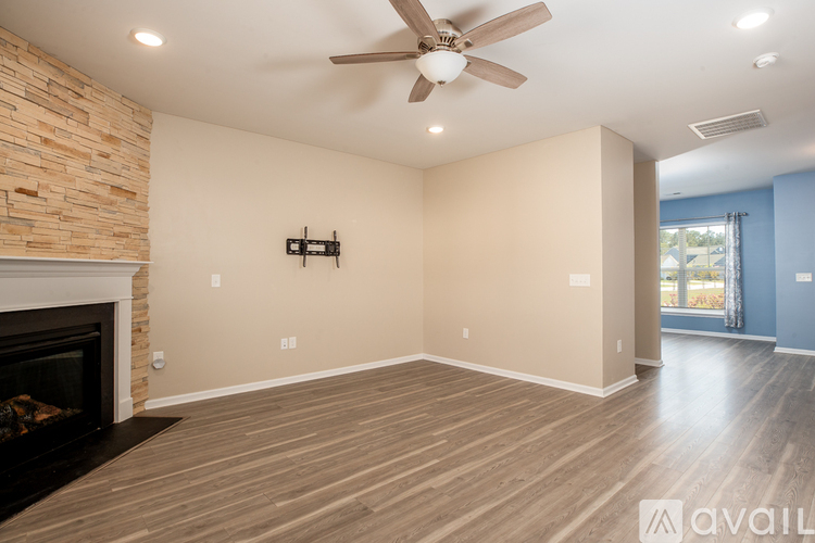 A spacious living room with a fireplace and wood flooring.