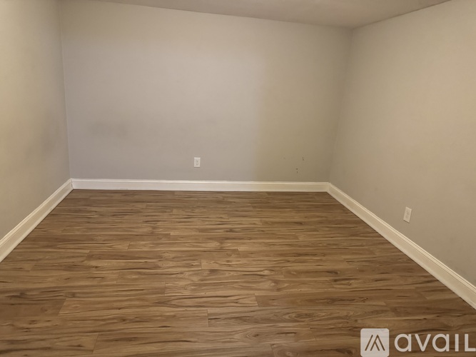 A room with wooden flooring and white walls.