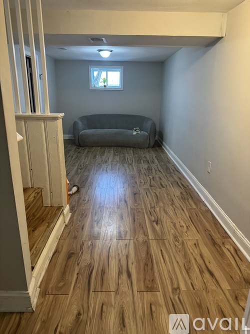 A living room with a grey sofa and wooden flooring.