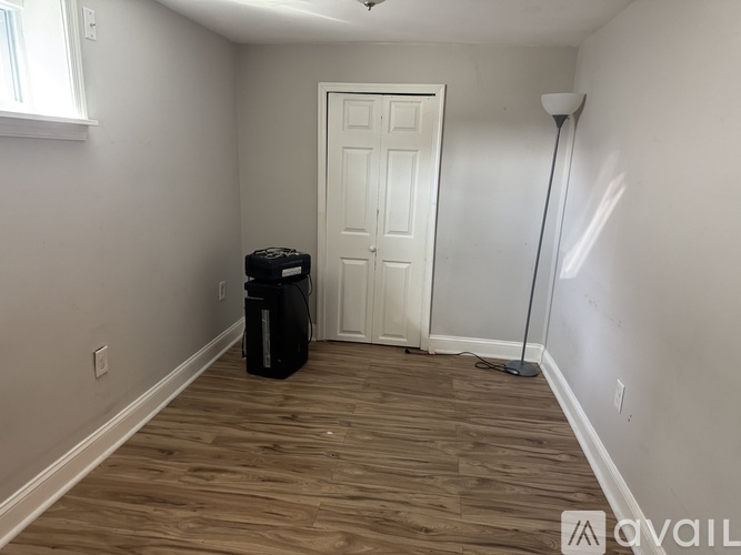 A room with a white door and a black trash can.