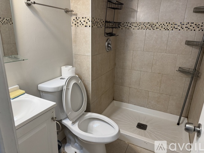 A white toilet in a tiled bathroom with a shower.