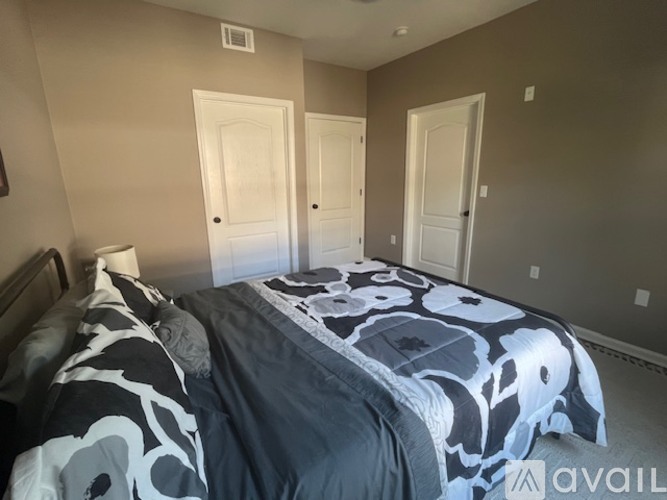 A bedroom with a bed covered in a black and white patterned comforter.