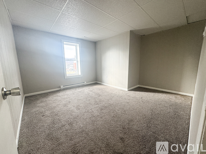 A room with a carpeted floor, a door, and a window.