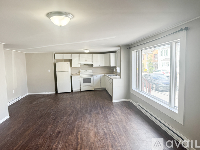 A kitchen with white appliances and wooden floors.