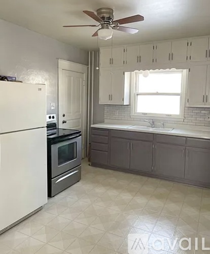 A kitchen with white cabinets and a black countertop.