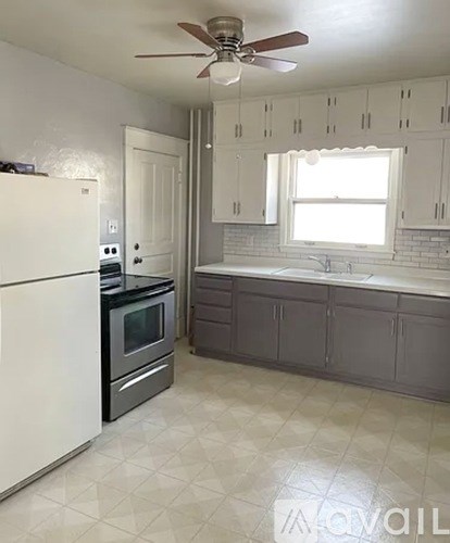 A kitchen with white cabinets and a black countertop.