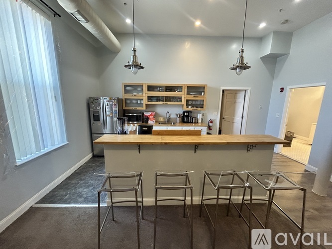 A kitchen area with a bar and chairs.