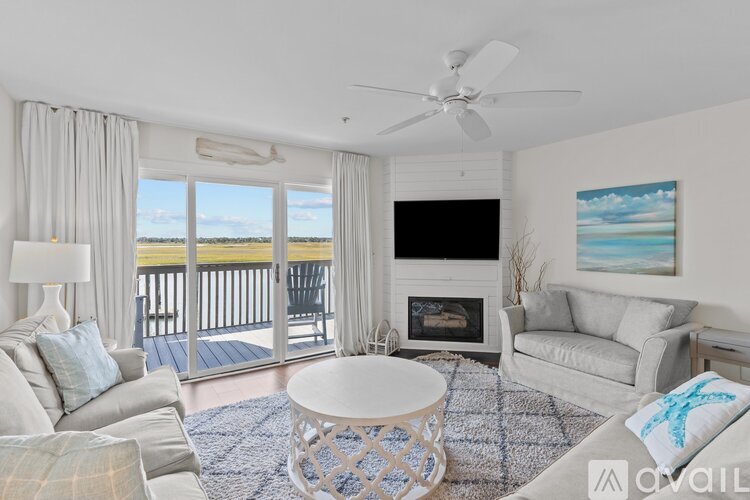 A living room with a fireplace, a television, and a view of the ocean.