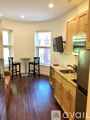 A kitchen with wooden floors and a refrigerator on the right side.