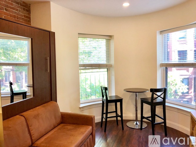 A living room with a brown couch, two chairs, and a small table.