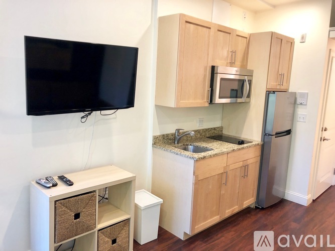 A kitchen with wooden cabinets and a black television mounted on the wall.