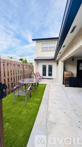 A patio with a table and chairs is in front of a house.