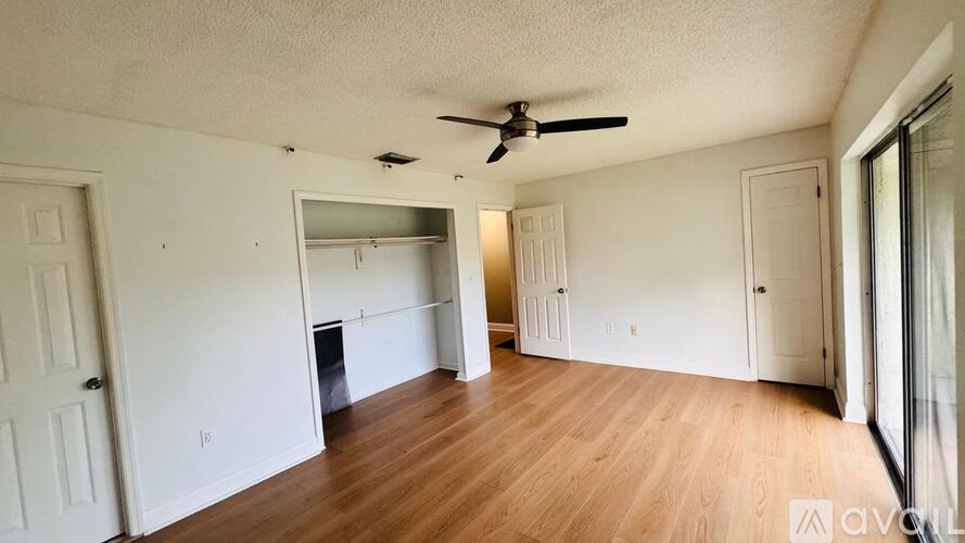 A spacious room with a ceiling fan and wooden flooring.