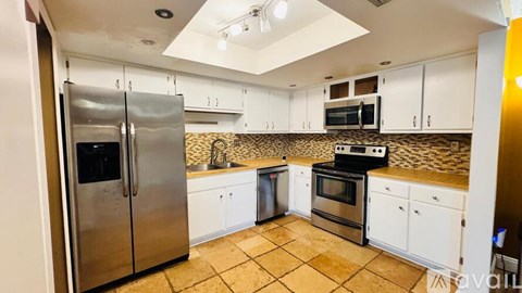 A kitchen with a refrigerator, microwave, oven, and cabinets.