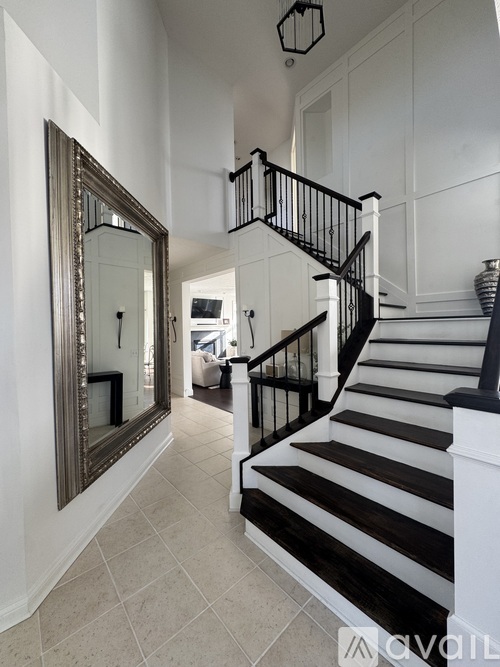 A large mirror is on the wall above a staircase.