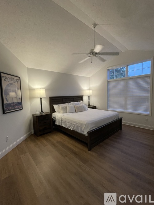 A bedroom with a bed, nightstands, and a ceiling fan.