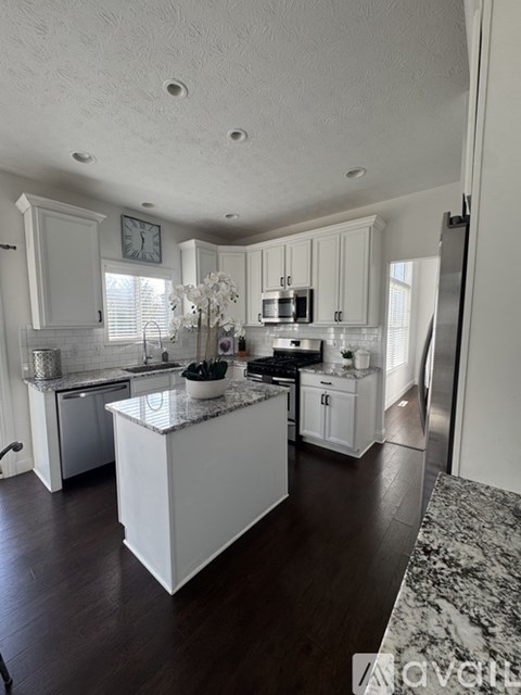 A kitchen with white cabinets and a marble countertop.