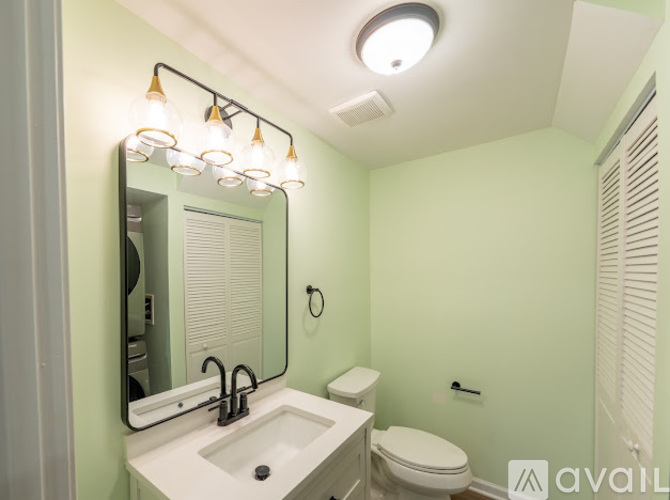 A bathroom with a sink, toilet, and mirror.