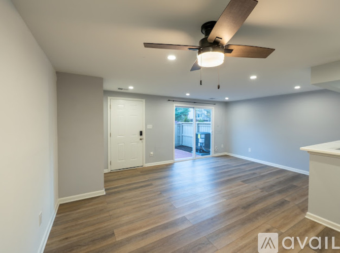 A spacious room with a ceiling fan and wooden flooring.