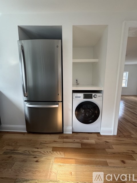A modern kitchen with a stainless steel refrigerator and a white washing machine.