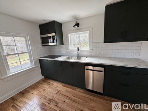 A kitchen with black cabinets and a white sink.