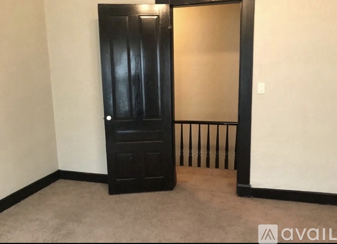 A black door with a handle is in a room with a carpet floor.