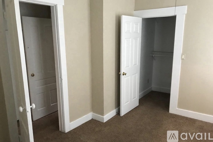 A room with two white doors and carpeted flooring.
