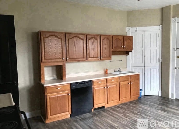 A kitchen with wooden cabinets and a black chair.