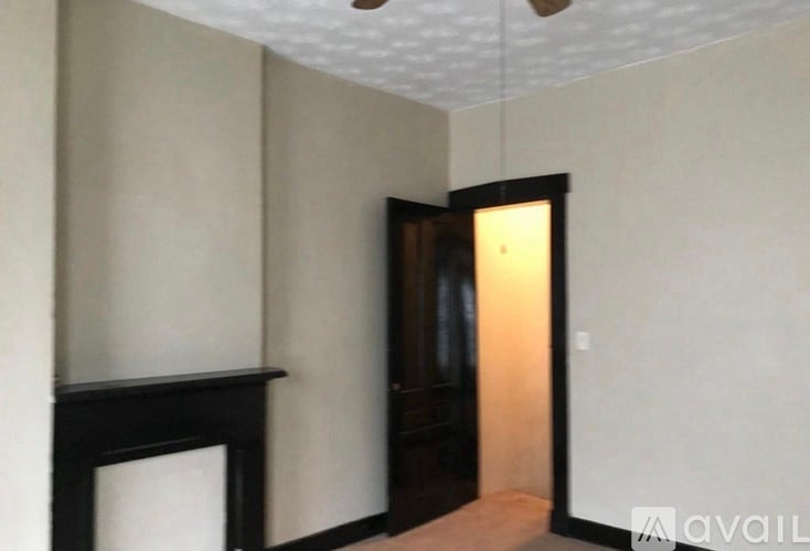 A room with a fireplace and a doorway leading to another room.