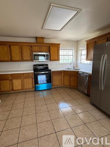 A kitchen with wooden cabinets and a stainless steel refrigerator.