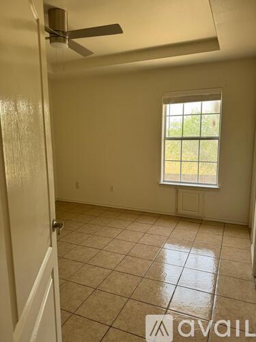 A room with a window and a fan on the ceiling.
