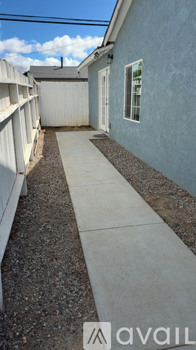 A narrow alley with a concrete pathway and a blue wall on the right.