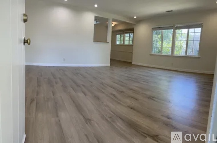 A spacious room with wooden flooring and a large mirror on the wall.