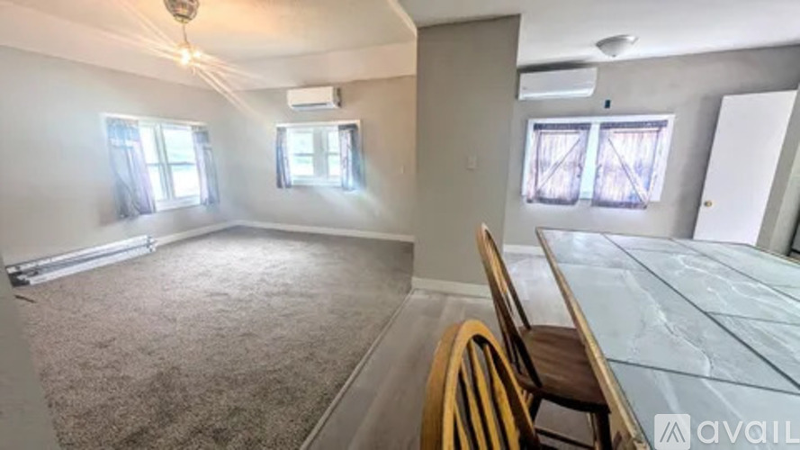 A room with a carpeted floor, a glass table, and two chairs.