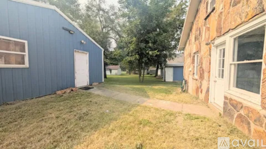A blue building with a white door is on the left and a stone building with a window is on the right.
