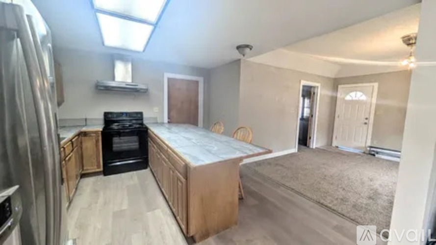 A kitchen with a refrigerator, oven, and a bedroom with a bed and a doorway leading to another room.