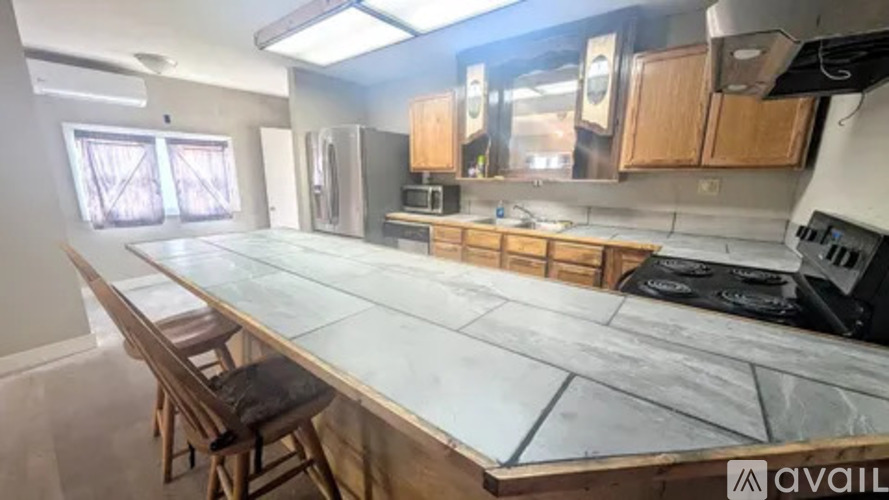 A kitchen with a long countertop and a stove top oven.