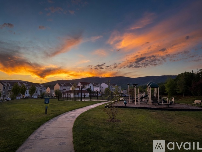 A park with a playground and a walking path under a colorful sky.