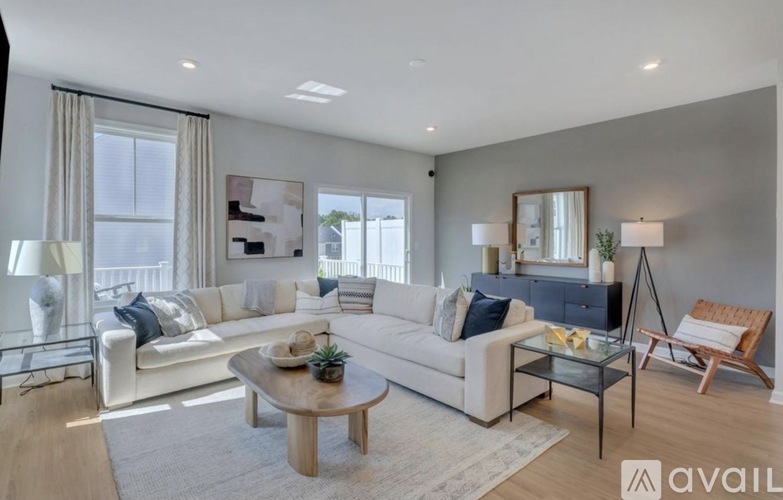 A modern living room with a white sofa, wooden coffee table, and a glass side table.
