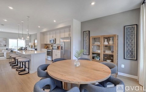 A modern kitchen with a wooden table surrounded by grey chairs.