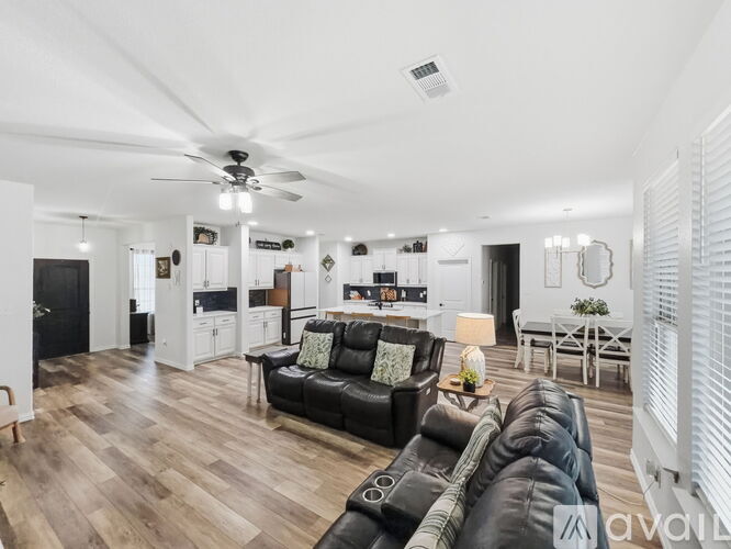 A living room with a black leather couch and wooden floors.