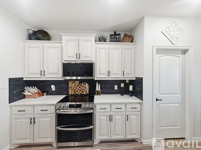 A kitchen with white cabinets and black appliances.