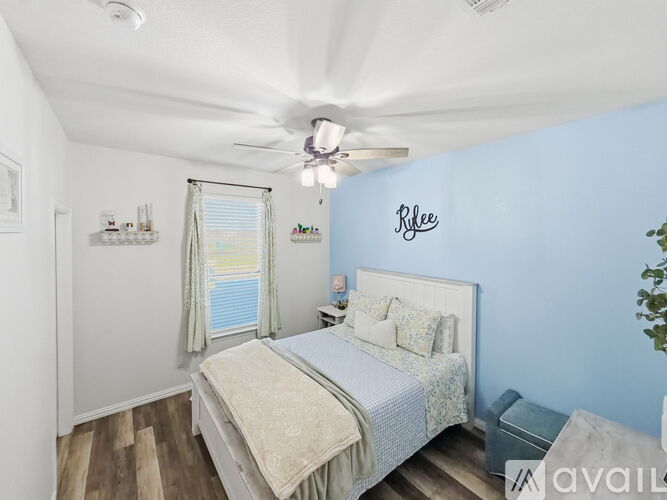 A bedroom with a bed, a ceiling fan, and a window with curtains.