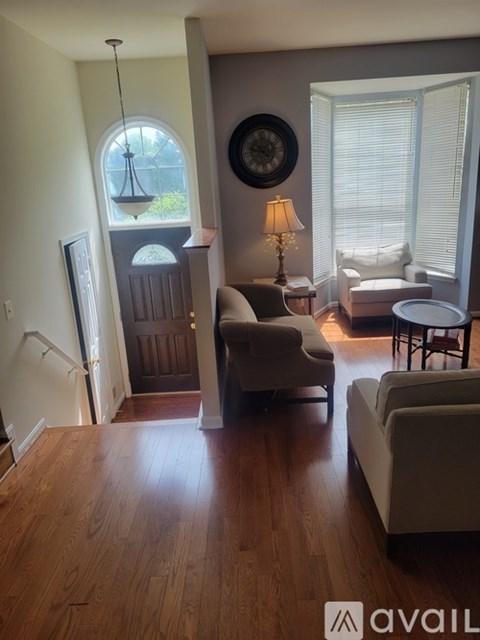 A living room with a couch, chair, and a table with a lamp on it.